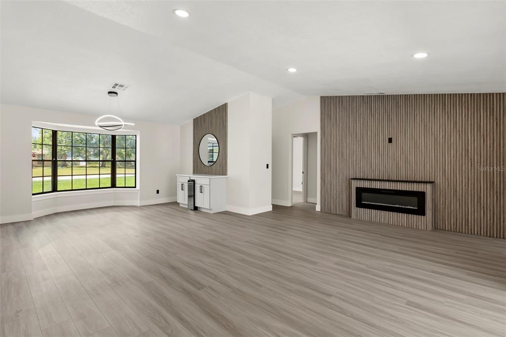 A living room features light wood flooring, a slatted wood accent wall, and a fireplace — 3007 FAYSON CIRCLE, DELTONA, FL