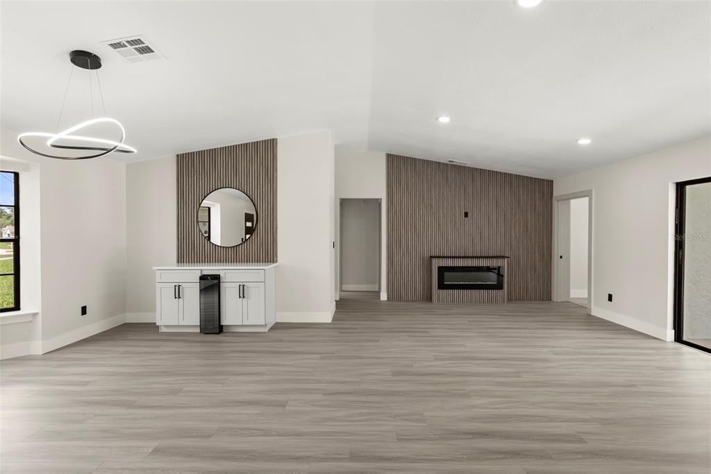 A living room features light wood-look flooring, a fireplace, and wood-slat accent walls — 3007 FAYSON CIRCLE, DELTONA, FL