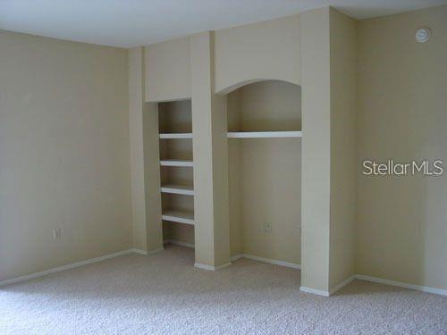 A carpeted room features a beige wall with built-in shelving and an arched alcove — 1321 ARBOR VISTA LOOP UNIT 209, LAKE MARY, FL