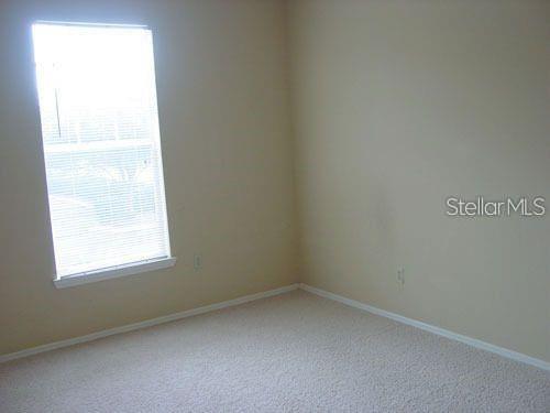 An empty bedroom features beige walls, light-colored carpet, and a single window with blinds — 1321 ARBOR VISTA LOOP UNIT 209, LAKE MARY, FL