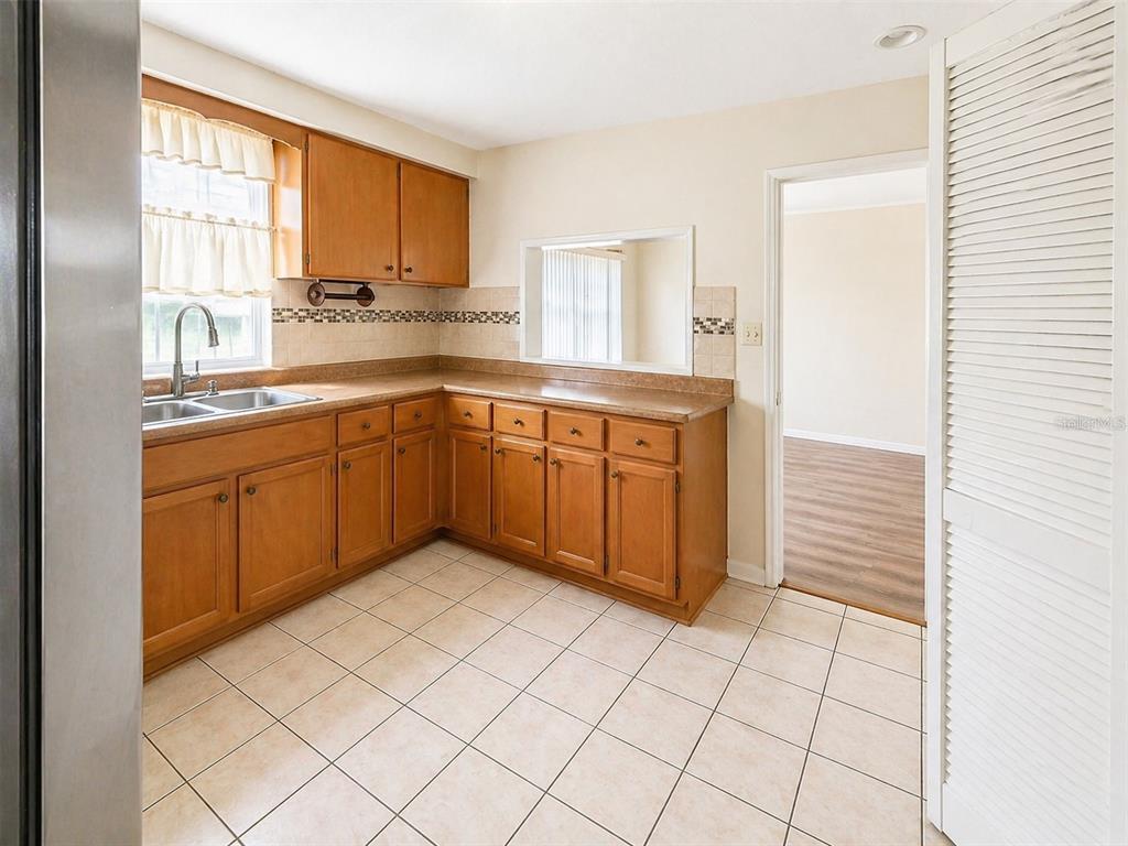 A kitchen with wood cabinets, tiled floors, and a pass-through window to an adjacent room — 5230 11TH AVENUE S, GULFPORT, FL
