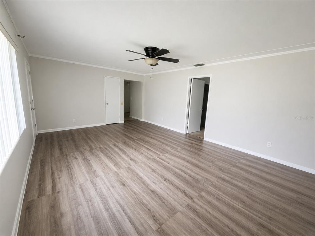 An empty room features light gray walls, wood-look flooring, and a ceiling fan — 5230 11TH AVENUE S, GULFPORT, FL