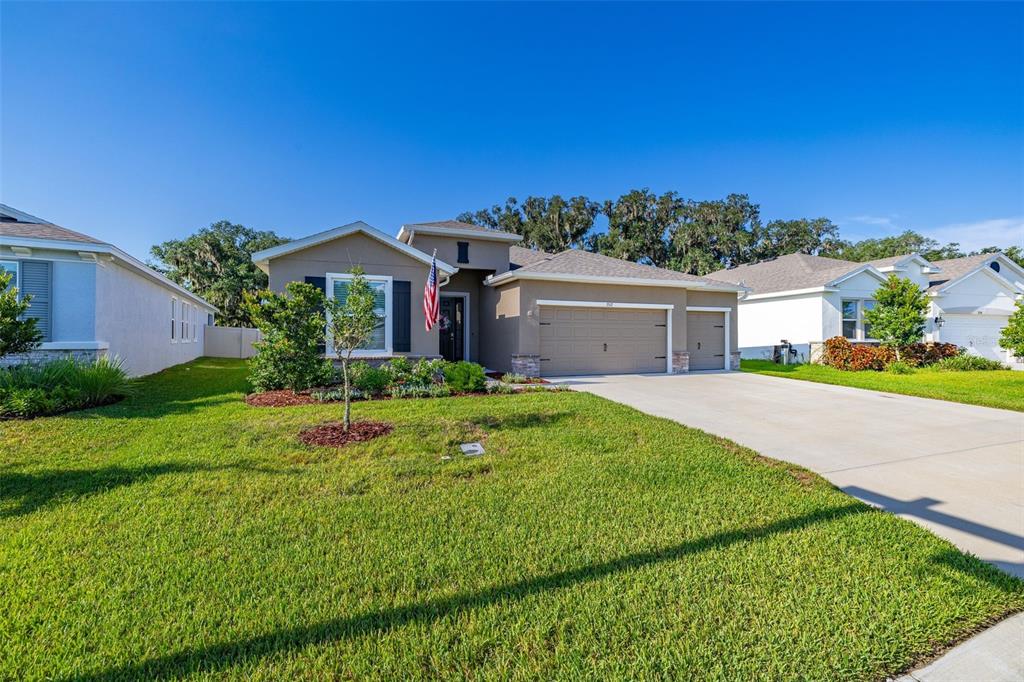 A tan single-story suburban house with a two-car garage and a front yard — 3512 CROOKED RIVER DRIVE, PLANT CITY, FL