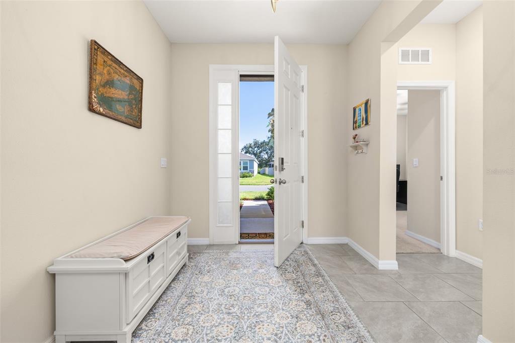 An entryway features a white storage bench, a patterned rug, and an open front door — 3512 CROOKED RIVER DRIVE, PLANT CITY, FL