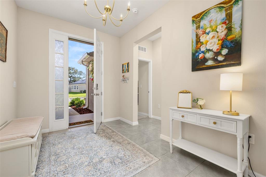 A bright entryway features tile flooring, a white console table, a bench, and an open door — 3512 CROOKED RIVER DRIVE, PLANT CITY, FL