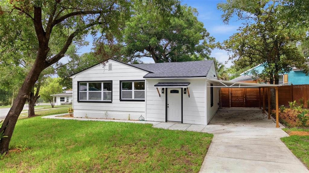 A white, single-story house with a black roof and an attached carport on the right — 2102 E HOWELL STREET, TAMPA, FL