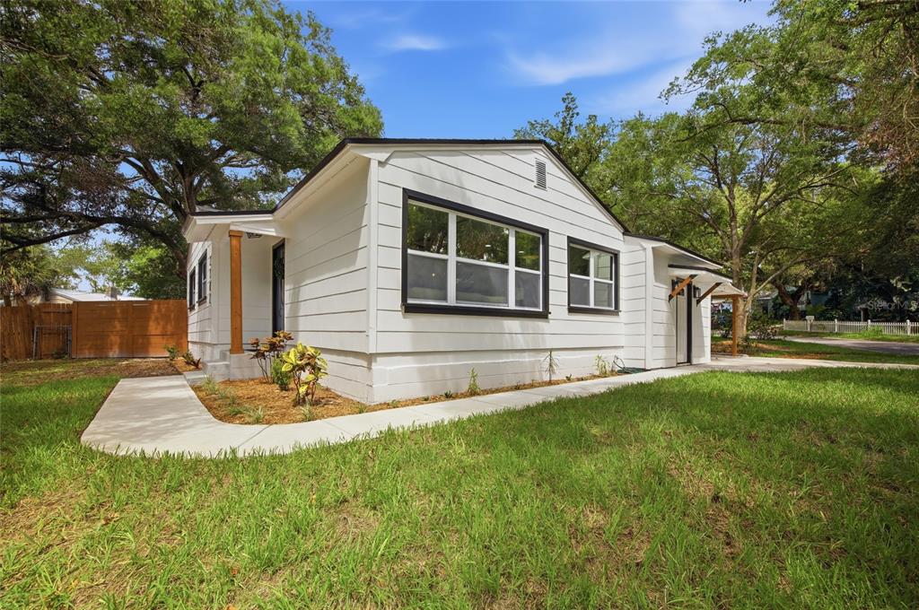 A white house with black window frames and a concrete walkway sits on a lawn — 2102 E HOWELL STREET, TAMPA, FL