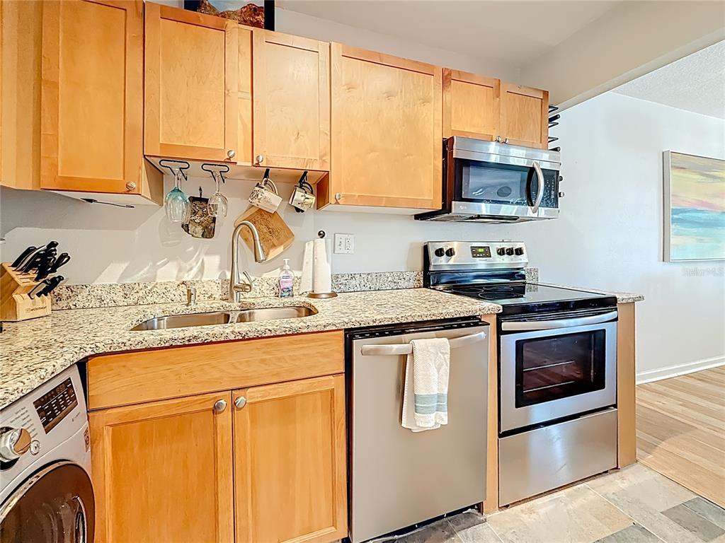 A kitchen features light wood cabinets, granite countertops, and stainless steel appliances — 3893 POMPANO DRIVE SE UNIT C, ST PETERSBURG, FL
