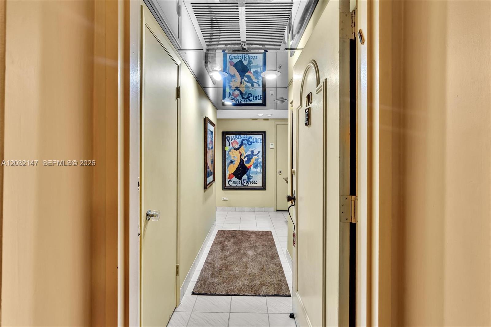 A narrow hallway features a mirrored ceiling, tiled floors, and a framed vintage poster — 800 NE 195th St # 710, Miami FL 33179, MIAMI, FL