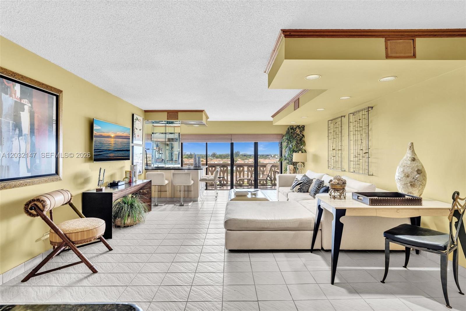 A living room features light tile floors, a sectional sofa, and a built-in bar area — 800 NE 195th St # 710, Miami FL 33179, MIAMI, FL