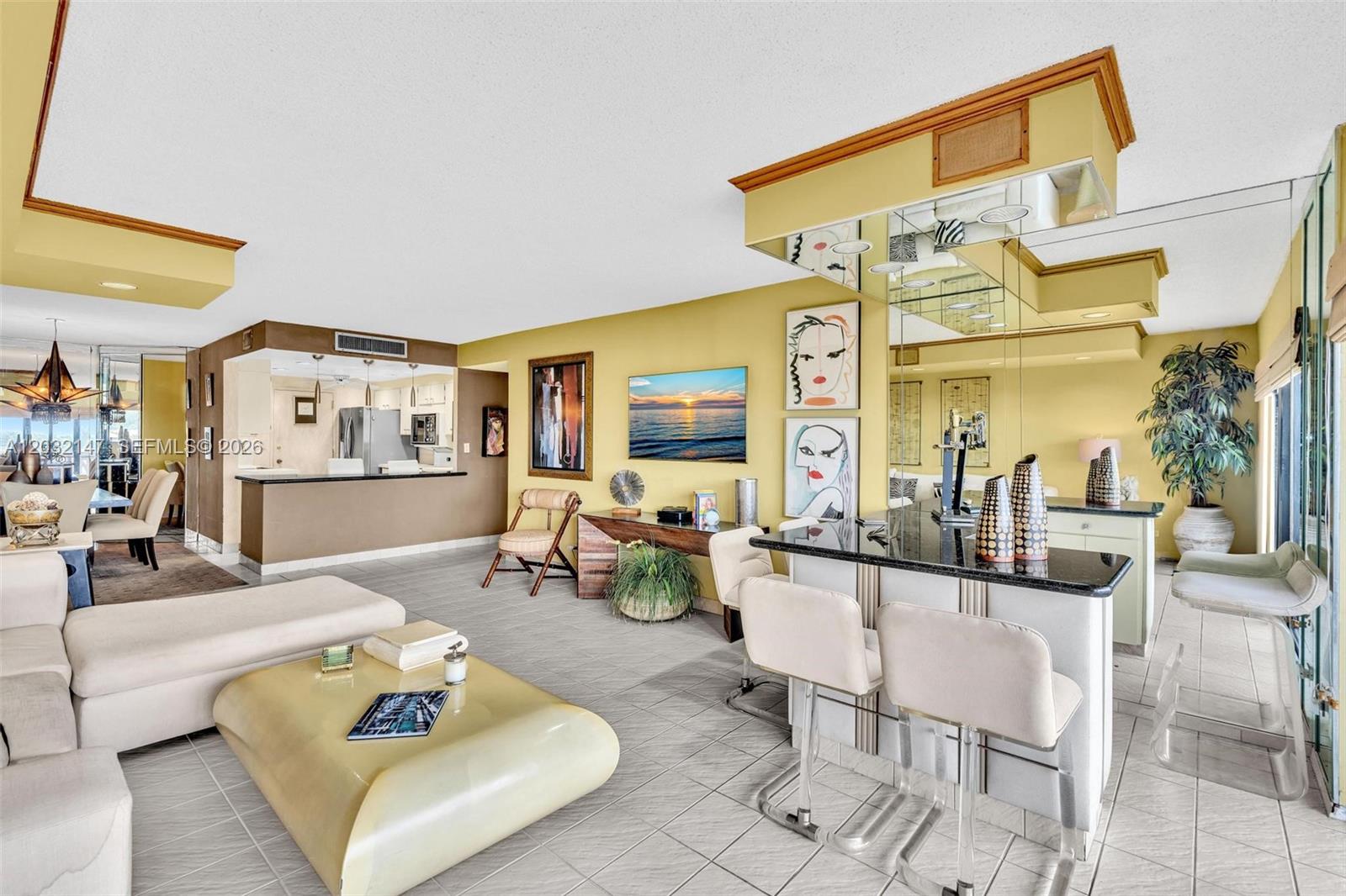A living room with a bar, tile floors, and yellow walls features a sectional sofa — 800 NE 195th St # 710, Miami FL 33179, MIAMI, FL