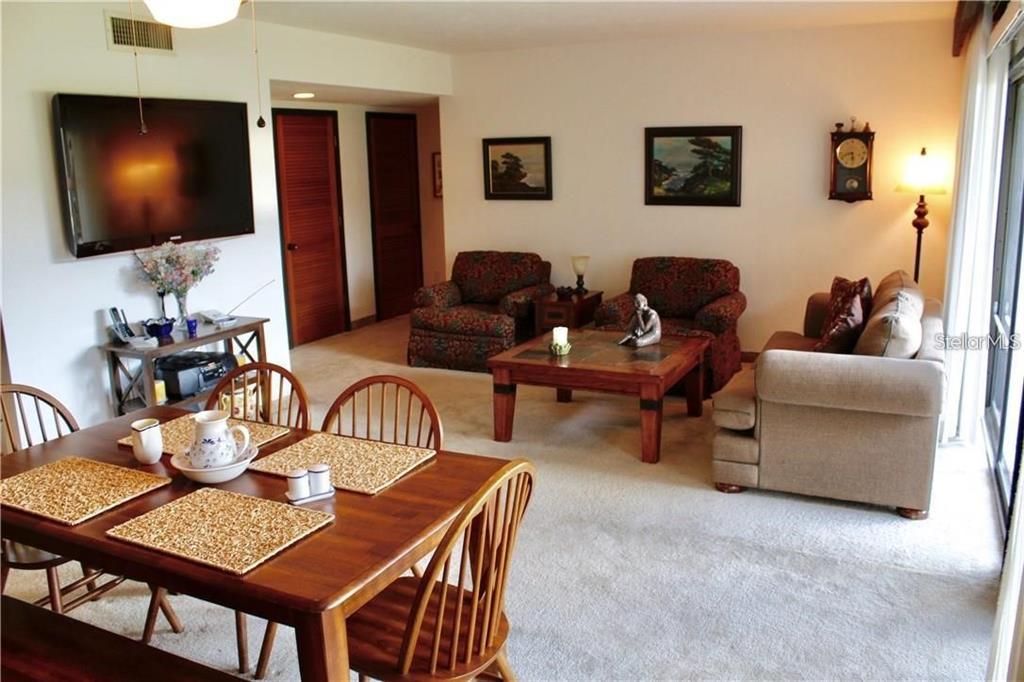 A living room and dining area with a wooden table, chairs, and upholstered furniture — 901 TENNIS WAY UNIT 3141, HAINES CITY, FL