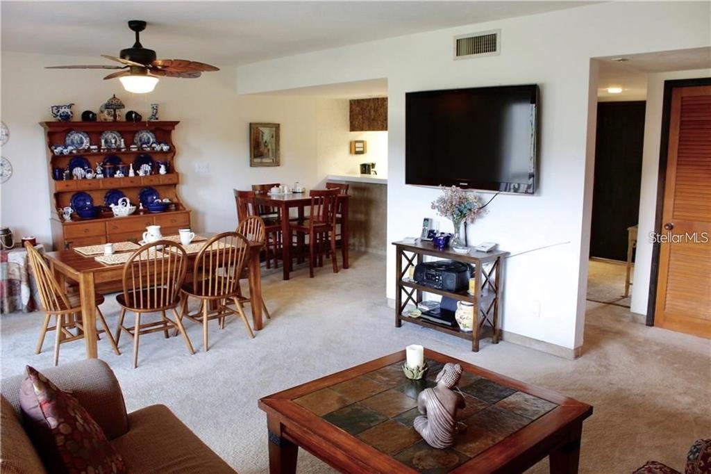 A living and dining area features a wooden hutch, a dining table, and a television — 901 TENNIS WAY UNIT 3141, HAINES CITY, FL