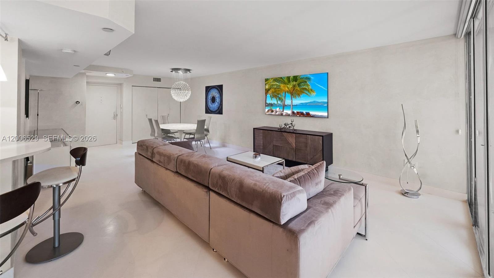 A modern living room features a velvet sectional sofa, a dining area, and a wall-mounted television — 1900 Sunset Harbour Dr # 2008, Miami Beach FL 33139, MIAMI BEACH, FL