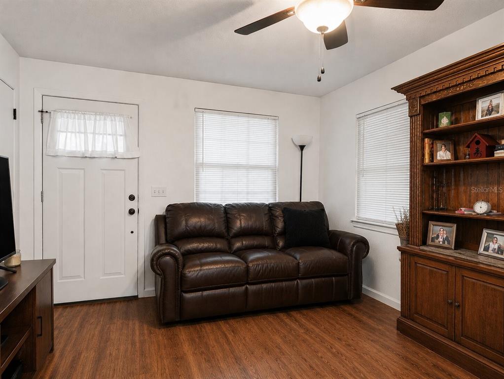 A living room features a brown leather sofa, wood-look flooring, and a tall wooden bookshelf — 2508 AVENUE A SW, WINTER HAVEN, FL
