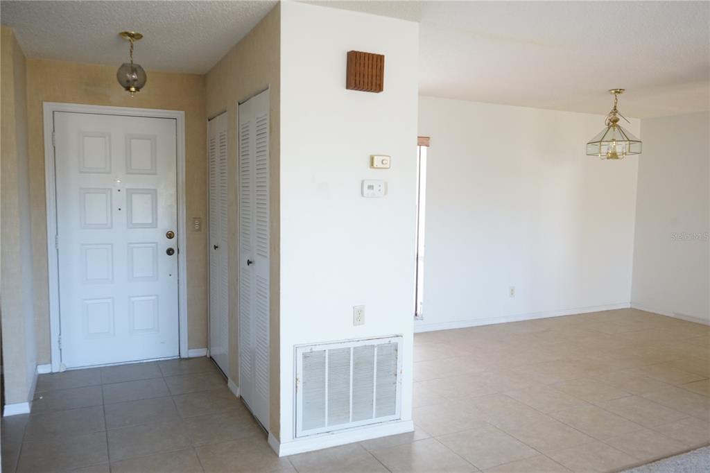 An entryway with a white door, louvered closets, and tile flooring leads into a living area — 302 BRYCE COURT, SUN CITY CENTER, FL
