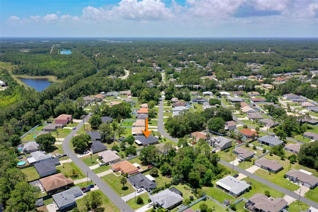 An aerial view shows a suburban neighborhood with an orange arrow pointing to a house — 25 PILLORY LANE, PALM COAST, FL