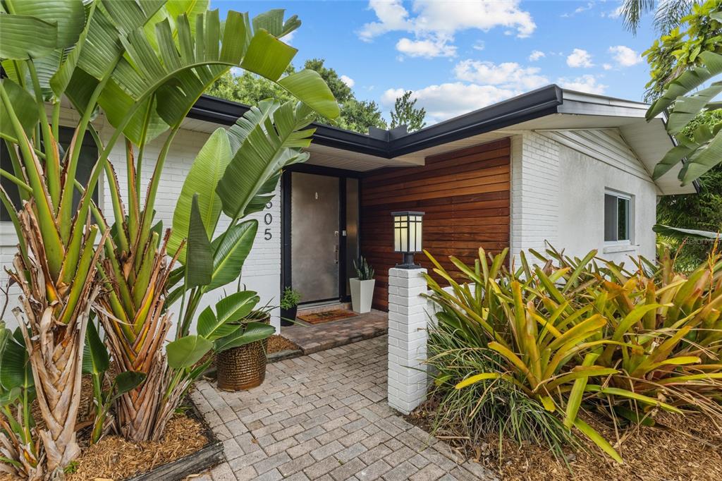 A brick walkway leads to a front entrance with wood siding and a metal door — 2605 BOTANY AVENUE, SARASOTA, FL