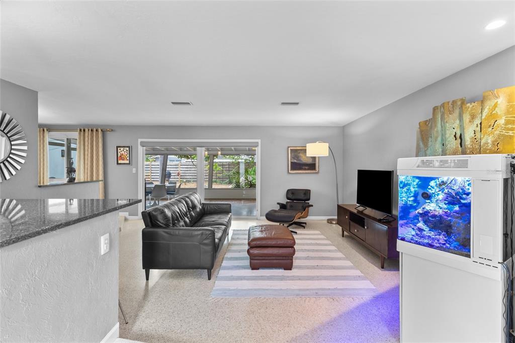 A living room features a black leather sofa, a fish tank, and a sliding glass door — 2605 BOTANY AVENUE, SARASOTA, FL