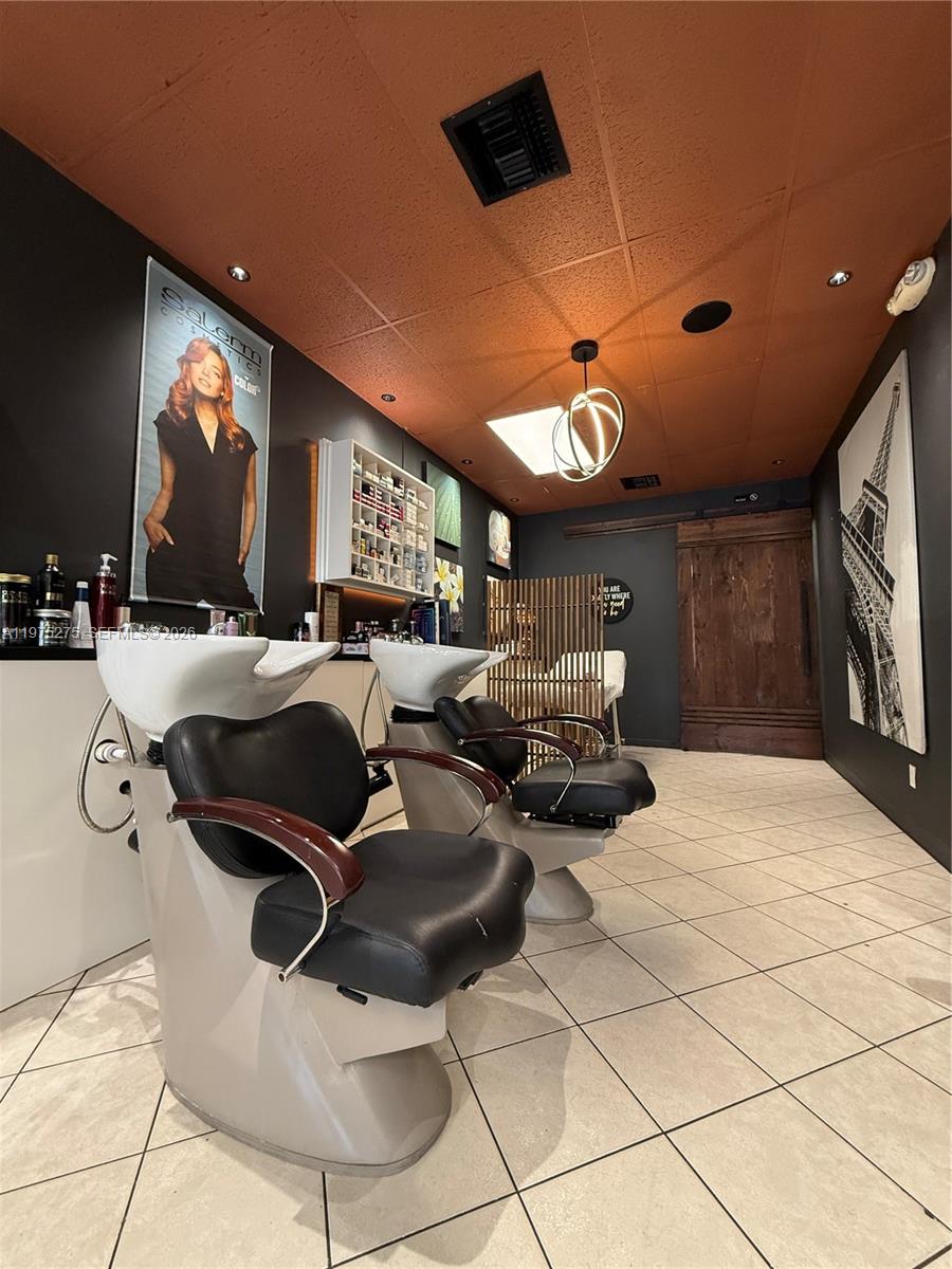 A hair salon features two shampoo stations, dark walls, a copper-colored ceiling, and tile flooring — 7764 NW 44, Sunrise FL 33351, SUNRISE, FL