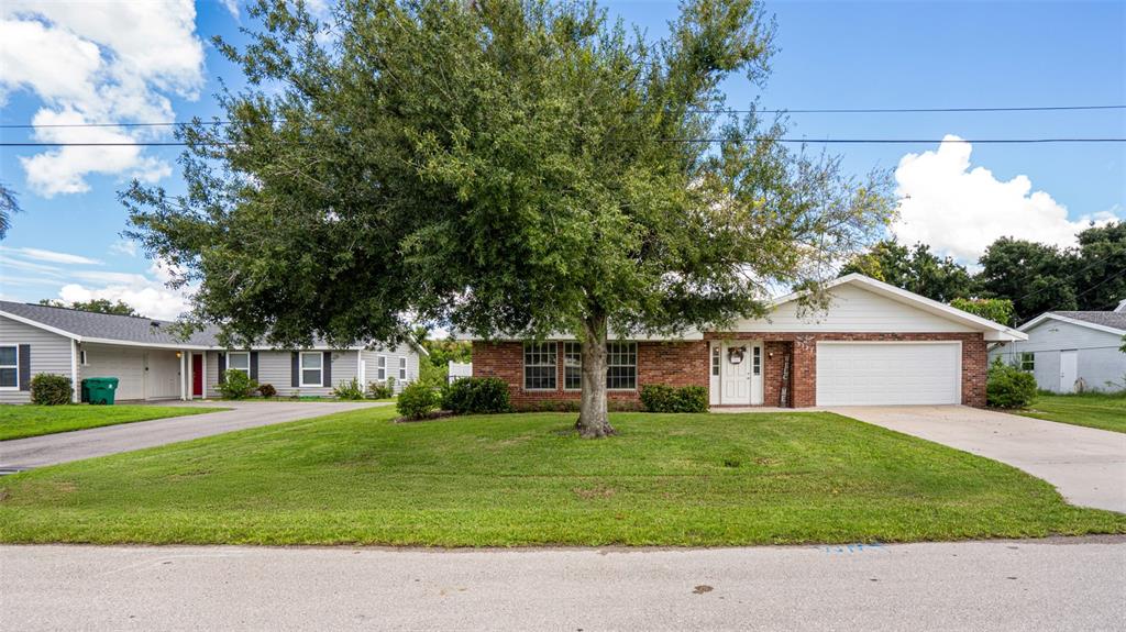 A single-story brick house with a white garage and a large tree in the yard — 3127 SHANNON DRIVE, PUNTA GORDA, FL