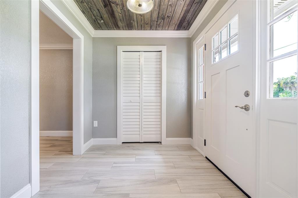 A foyer features light wood-look tile flooring, gray walls, and a dark wood-plank ceiling — 3127 SHANNON DRIVE, PUNTA GORDA, FL