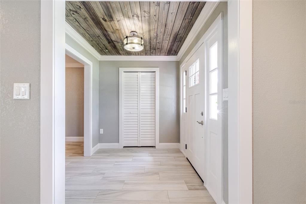 An entryway features a wood-plank ceiling, light tile flooring, and a white louvered closet door — 3127 SHANNON DRIVE, PUNTA GORDA, FL