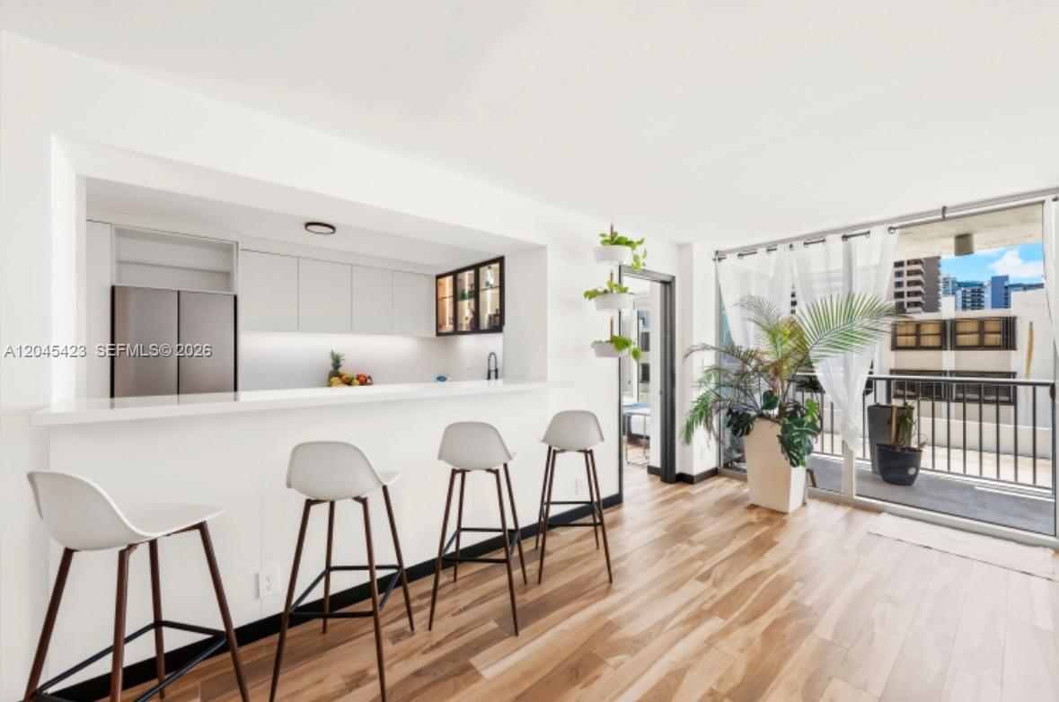 A modern kitchen with a breakfast bar and stools opens to a balcony with city views — 2655 Collins Ave # 504, Miami Beach FL 33140, MIAMI BEACH, FL