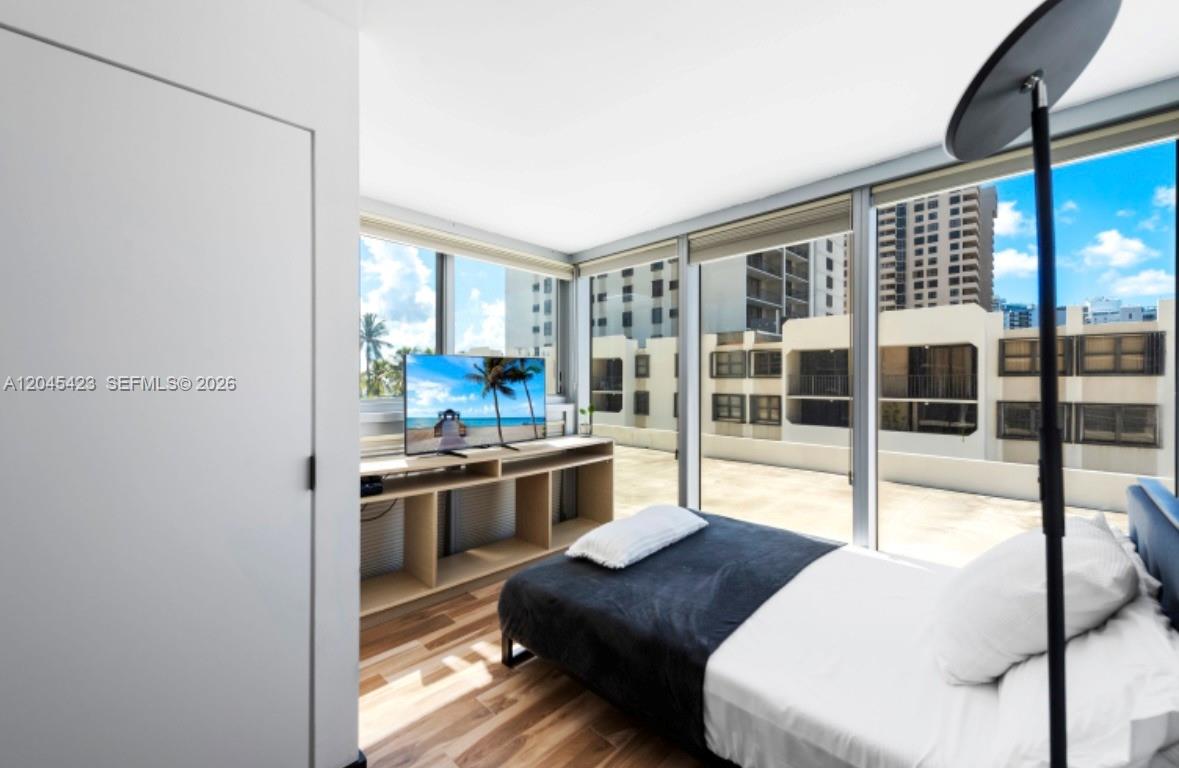 A bedroom features a bed, a media console with a television, and floor-to-ceiling windows — 2655 Collins Ave # 504, Miami Beach FL 33140, MIAMI BEACH, FL