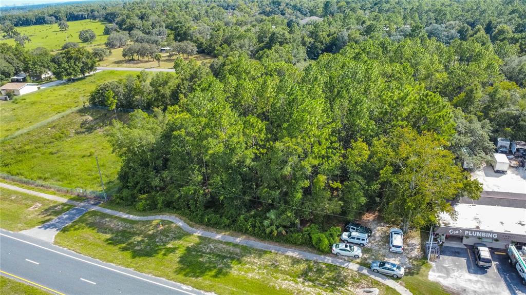 An aerial view shows a wooded lot located next to a road and a business — 4176 W GULF TO LAKE HIGHWAY, LECANTO, FL