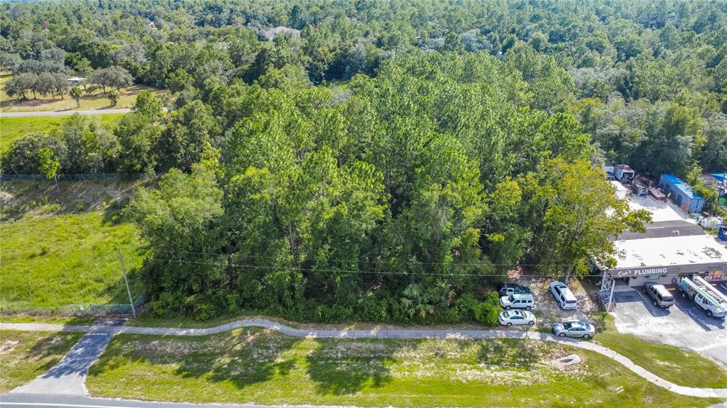An aerial view shows a wooded lot located next to a commercial plumbing business — 4176 W GULF TO LAKE HIGHWAY, LECANTO, FL