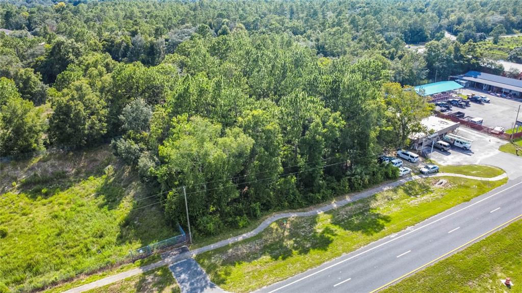An aerial view shows a wooded lot situated between a road and a commercial building — 4176 W GULF TO LAKE HIGHWAY, LECANTO, FL