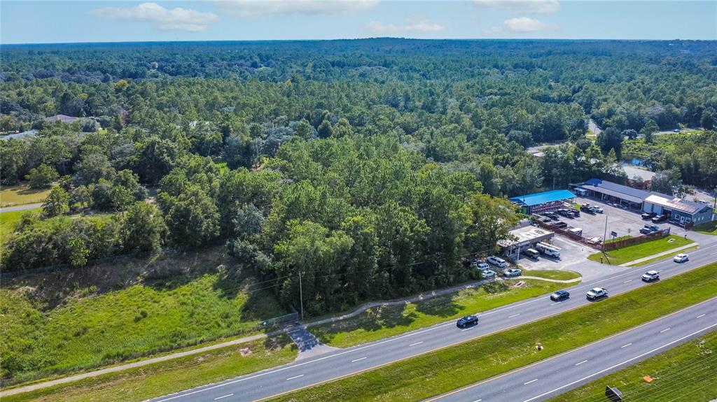 An aerial view shows a wooded lot adjacent to a commercial property and a highway — 4176 W GULF TO LAKE HIGHWAY, LECANTO, FL