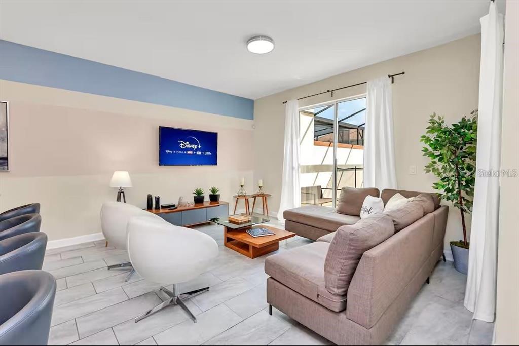 A living room features a sectional sofa, two swivel chairs, a wall-mounted television, and tile flooring — 1565 PLUNKER DRIVE, DAVENPORT, FL