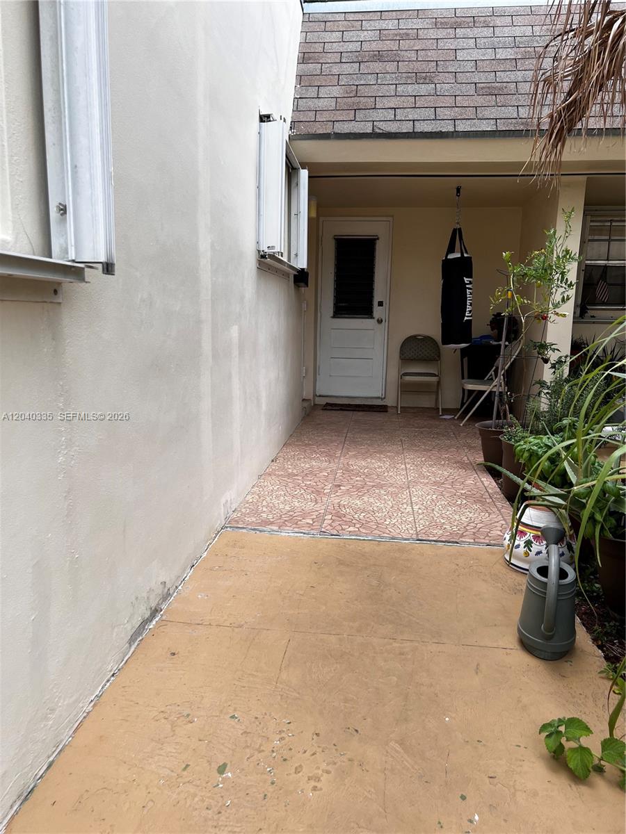 A covered outdoor patio features a tiled floor, a white door, and a punching bag — 11229 SW 169th St # V4742, Miami FL 33157, MIAMI, FL