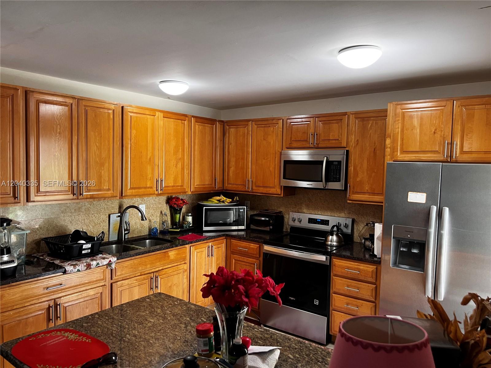 A kitchen features wood cabinets, granite countertops, stainless steel appliances, and a central island — 11229 SW 169th St # V4742, Miami FL 33157, MIAMI, FL