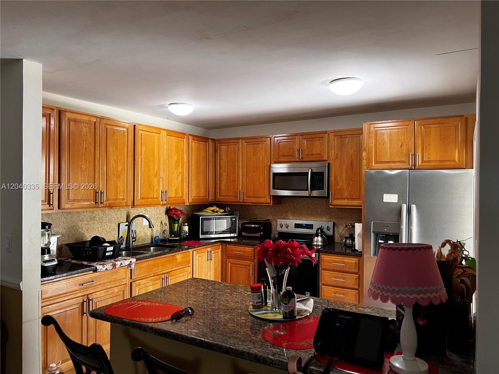 A kitchen features wood cabinets, granite countertops, stainless steel appliances, and a central island — 11229 SW 169th St # V4742, Miami FL 33157, MIAMI, FL