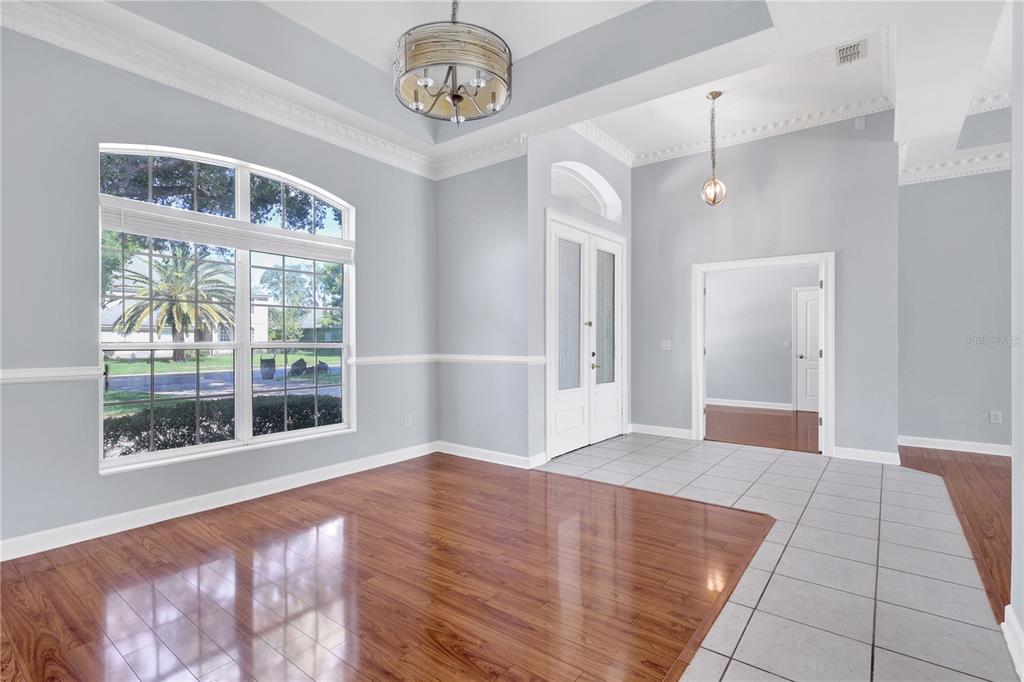 A dining room features hardwood floors, a tray ceiling with a chandelier, and large windows — 1337 BALLENTYNE PLACE, APOPKA, FL