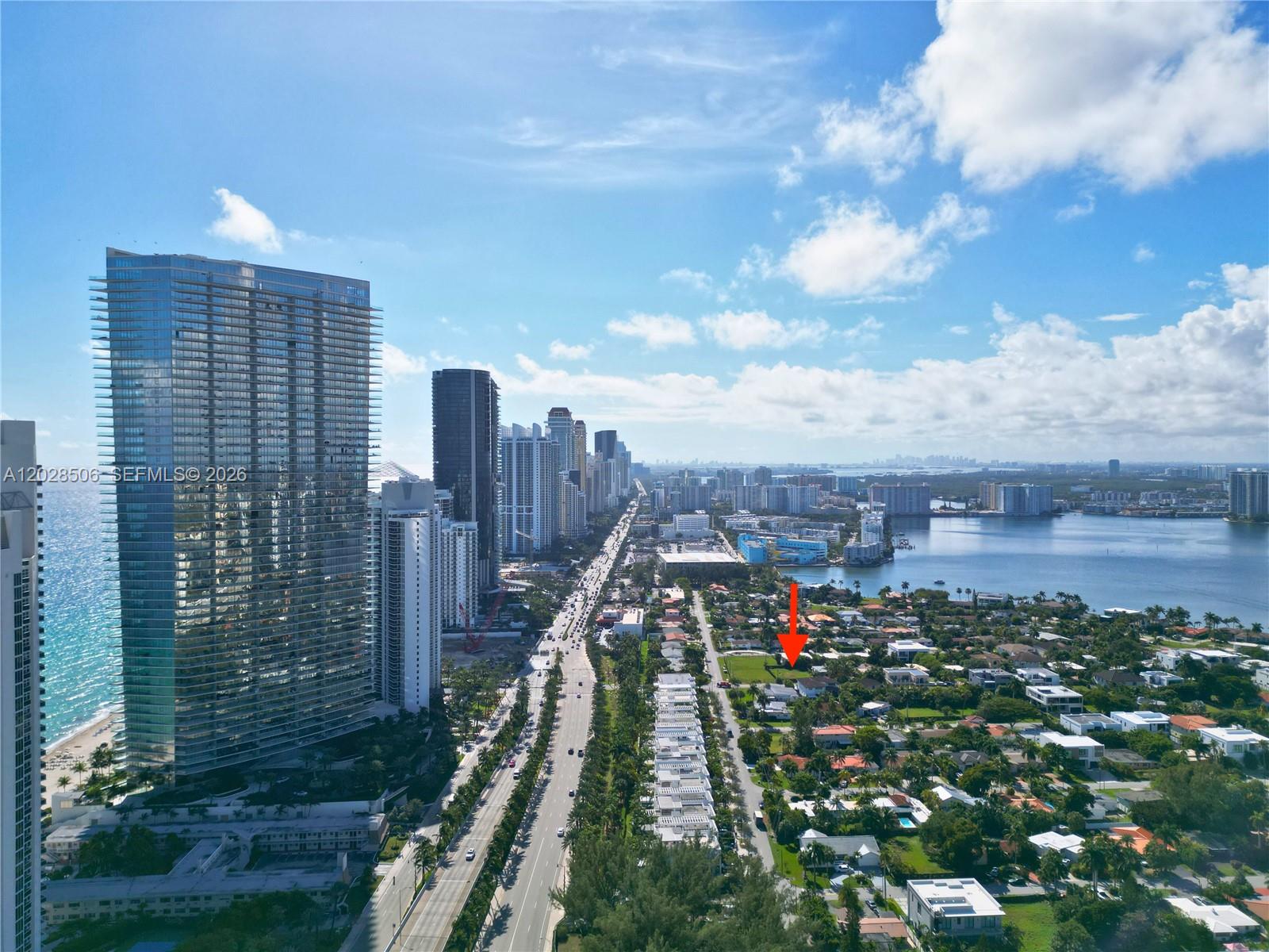 An aerial view shows a coastal city with high-rise buildings, a highway, and residential homes — 212 189th St, Sunny Isles Beach FL 33160, SUNNY ISLES BEACH, FL