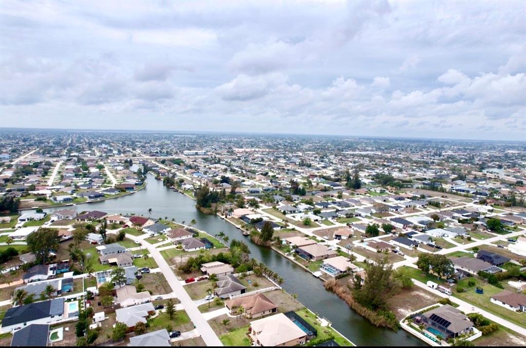 An aerial view shows a residential neighborhood with houses situated along a winding canal — 239 SW 28TH TERRACE, CAPE CORAL, FL