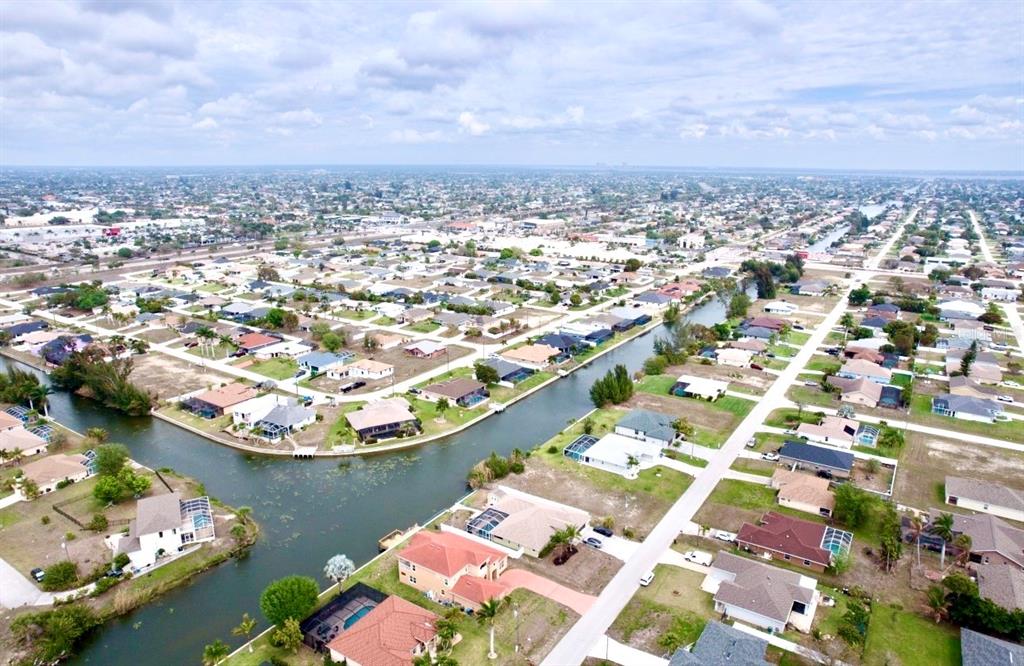 An aerial view shows a residential neighborhood with houses situated along a winding canal — 239 SW 28TH TERRACE, CAPE CORAL, FL