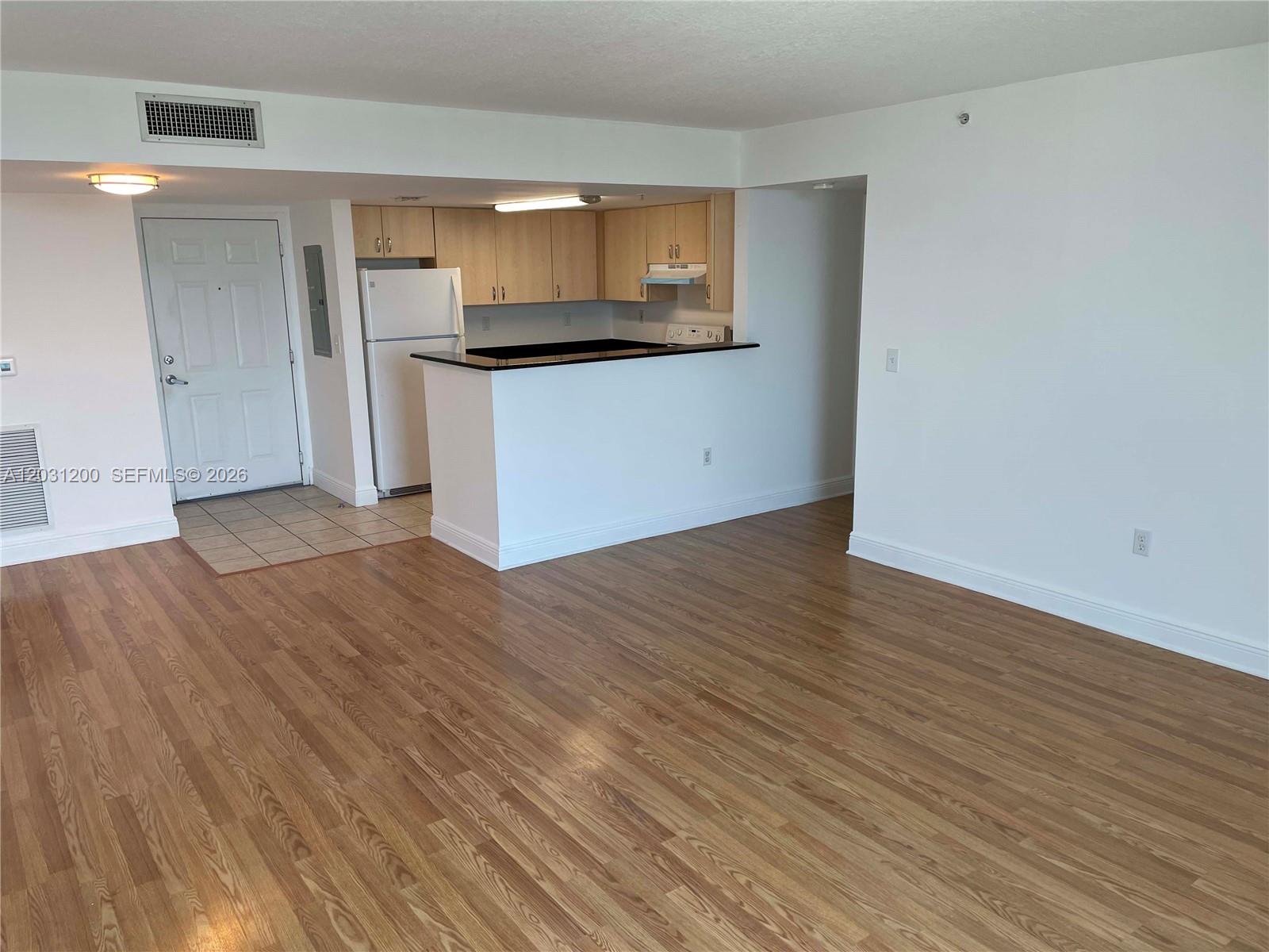 An open-concept living area features wood-look flooring and a kitchen with light wood cabinets — 3000 Coral Way # 1501, Miami FL 33145, MIAMI, FL