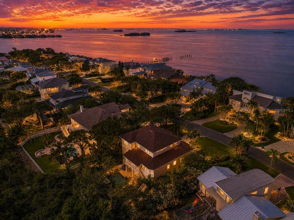 An aerial view of waterfront houses at sunset with lush trees and swimming pools — 897 POINT SEASIDE DRIVE, CRYSTAL BEACH, FL
