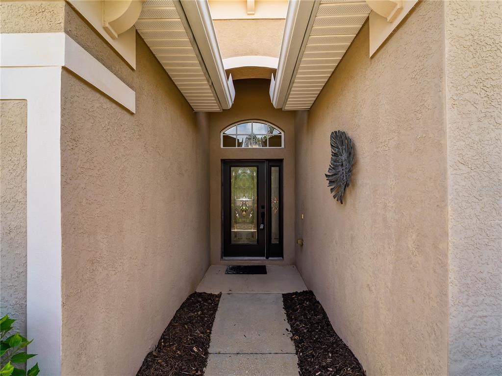 A concrete walkway leads to a front door with a decorative glass insert and transom — 5435 BLUE HERON CIRCLE, NORTH PORT, FL