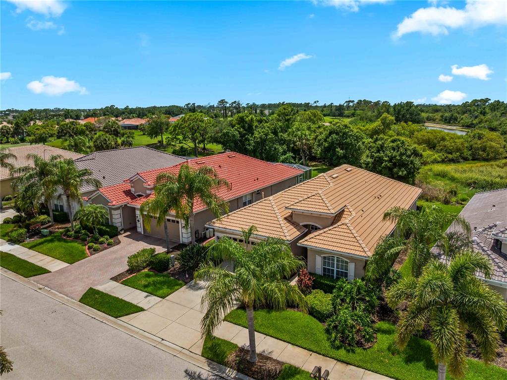 An aerial view shows two suburban houses with tile roofs and palm trees in Florida — 5435 BLUE HERON CIRCLE, NORTH PORT, FL