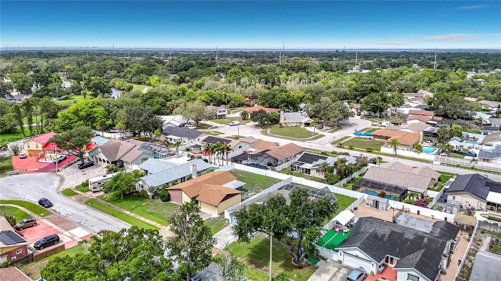 An aerial view shows a suburban neighborhood with single-family homes, green trees, and streets — 7010 COBBLEWOOD COURT, TAMPA, FL