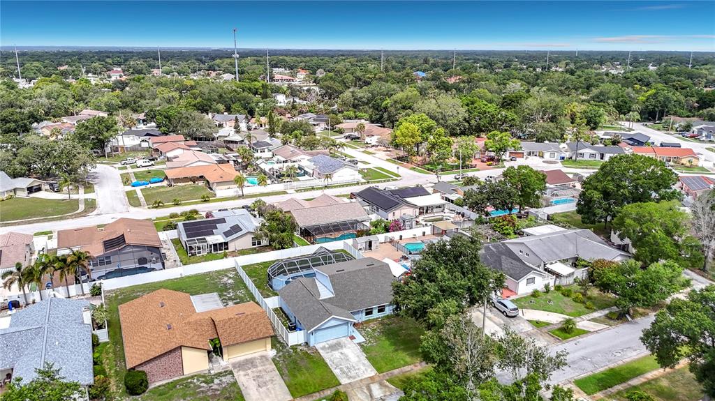 An aerial view shows a suburban neighborhood with single-family homes, swimming pools, and tree-lined streets — 7010 COBBLEWOOD COURT, TAMPA, FL