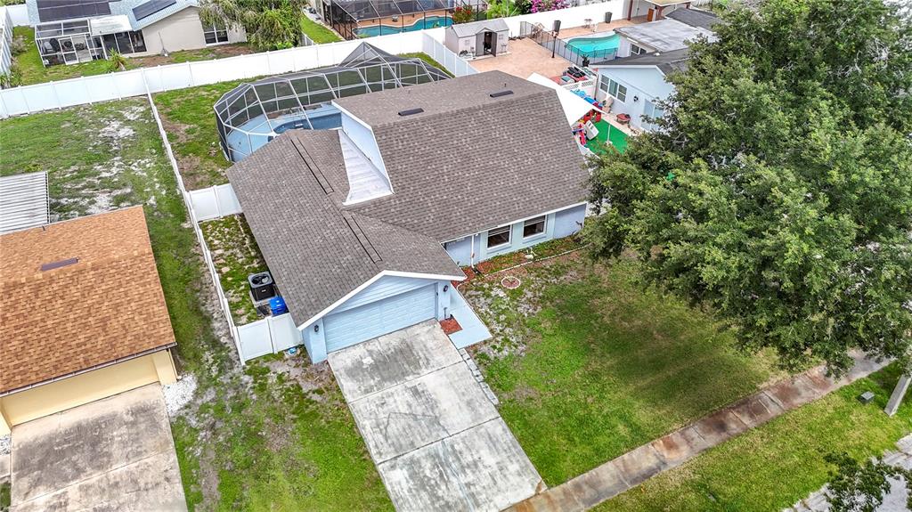 An aerial view shows a light blue house with a gray roof, garage, and pool enclosure — 7010 COBBLEWOOD COURT, TAMPA, FL