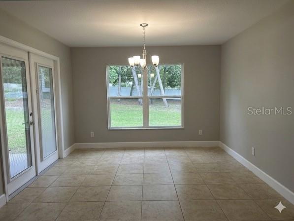 A dining area features light tile flooring, a central chandelier, and glass doors to the yard — 9670 SW 42ND AVENUE, OCALA, FL