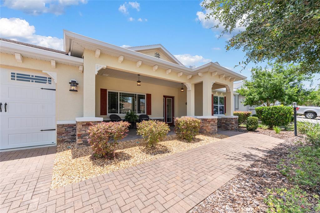 A single-story house features a covered front porch, stone accents, and a brick paver walkway — 9026 SW 89TH STREET ROAD, OCALA, FL